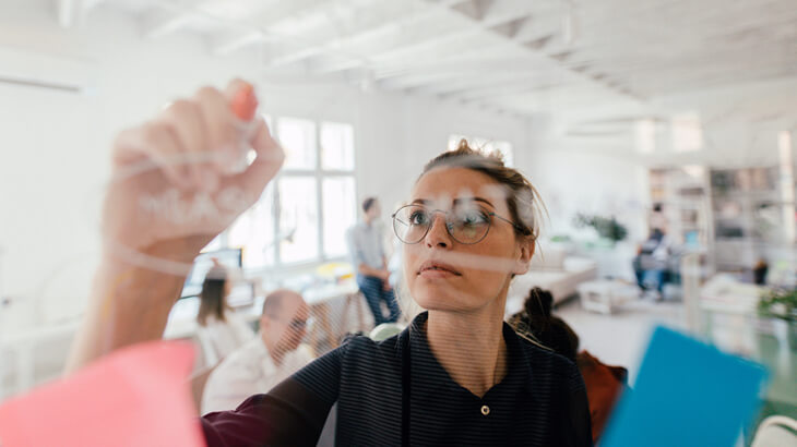 Women holding a book and writing on the screen.