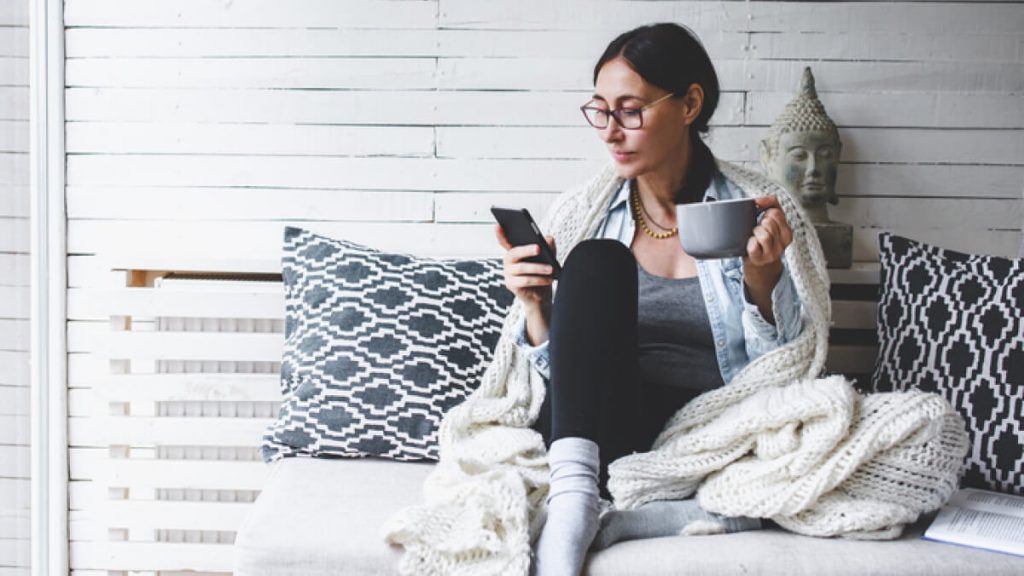 A women sitting on couch using phone