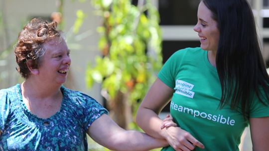 2 Women smiling at each other and holding hands.