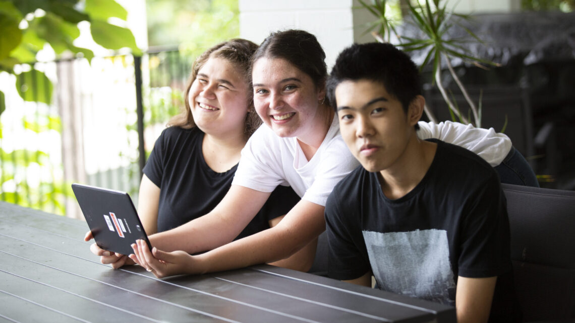 3 people sitting and looking at ipad.
