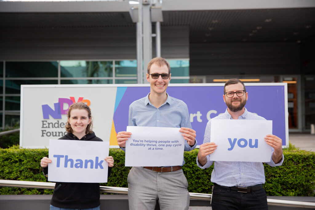 3 people out side support centre holding a word each