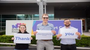 3 people outside support centre holding a word each