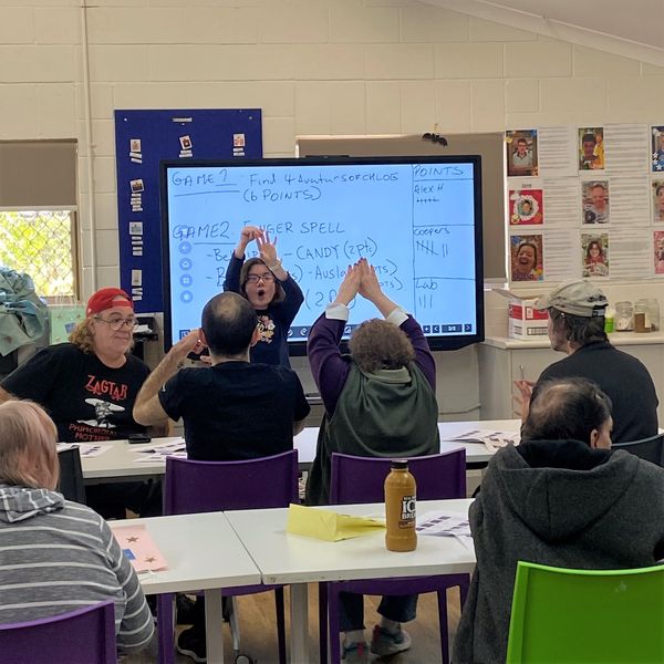 A client with a support worker teaching clients at Alex Hills Learning and Lifestyle Centre Auslan.