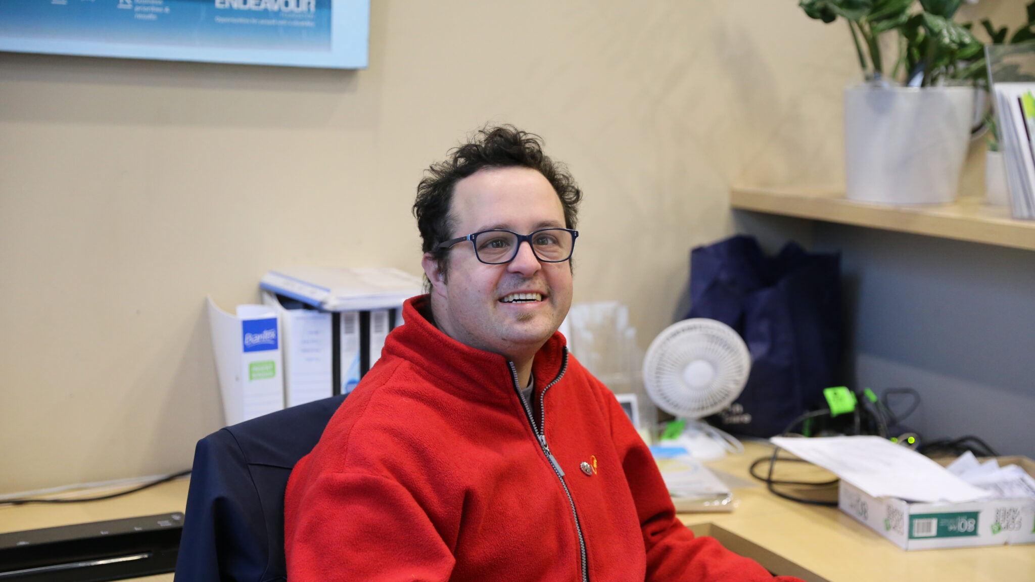 A man sitting and smiling behind a reception desk.