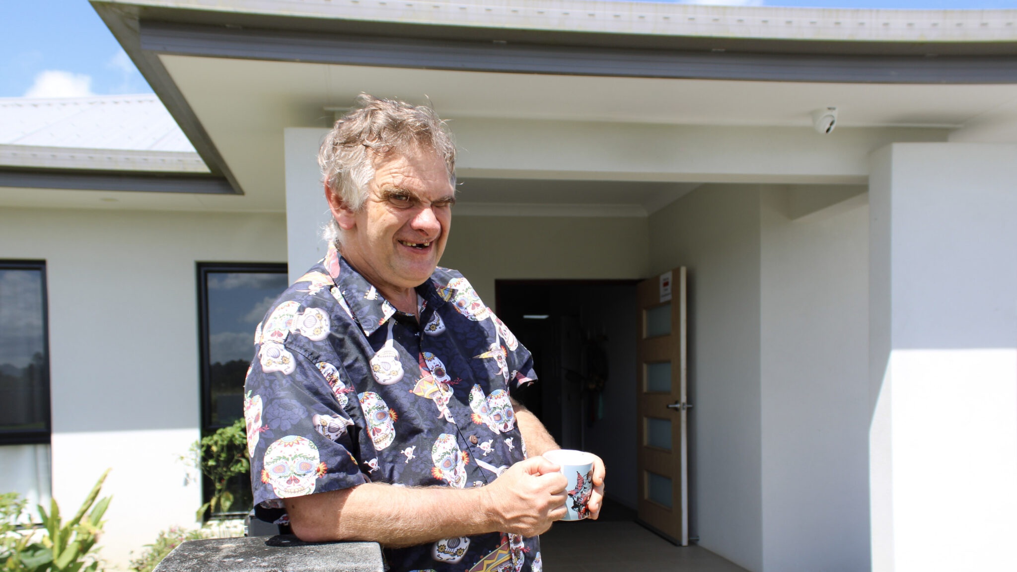 Man outside with cup in a supported independent living home.