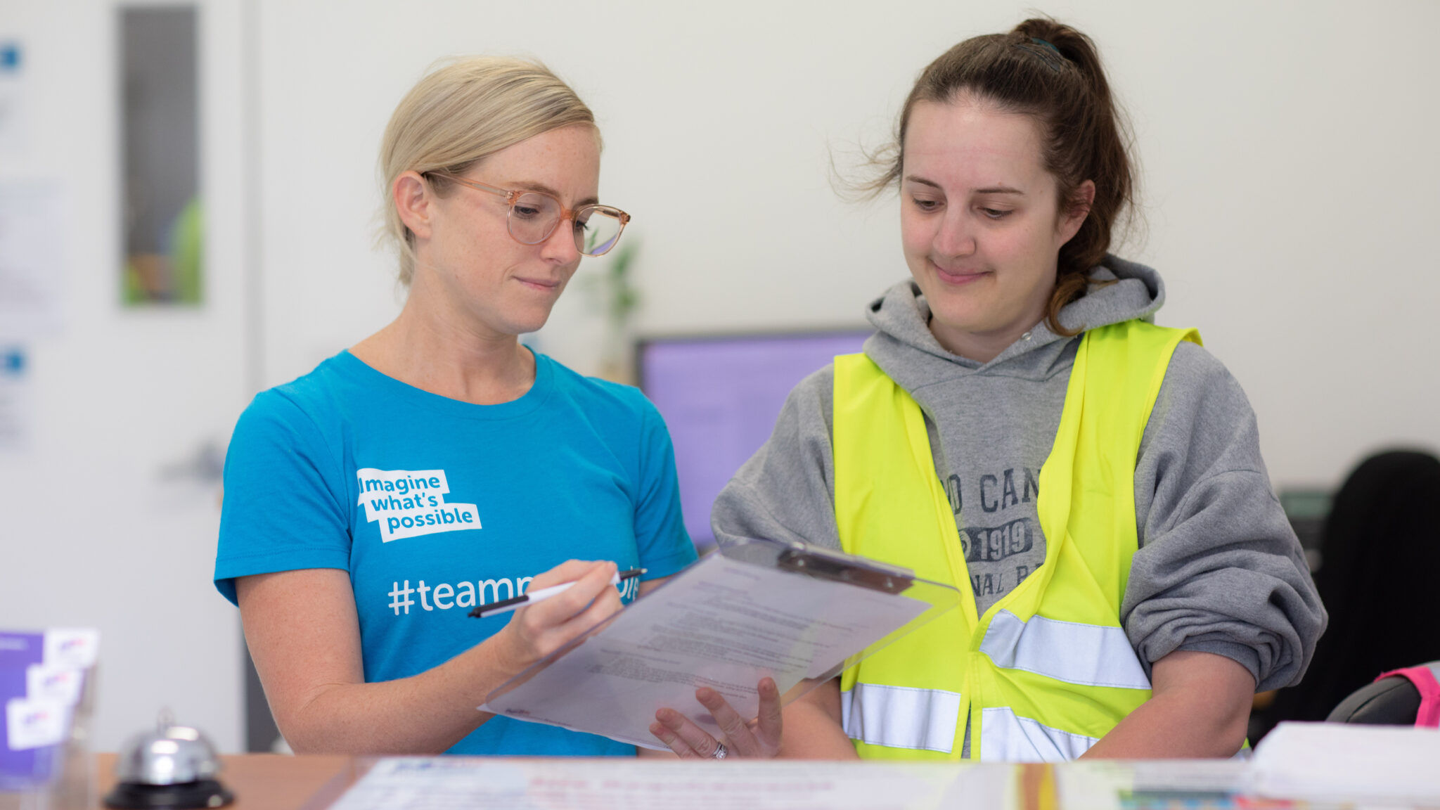 A woman smiling with a support worker going through a form.
