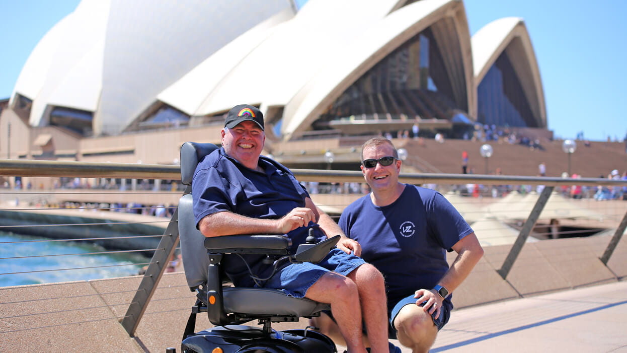 A customer with a support worker at Sydney Opera House getting their photo taken.
